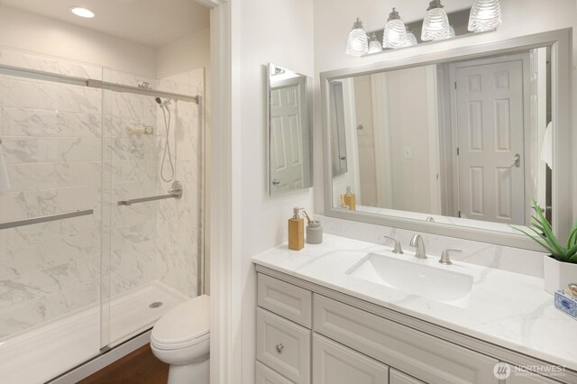 bathroom with a stall shower, toilet, vanity, and recessed lighting