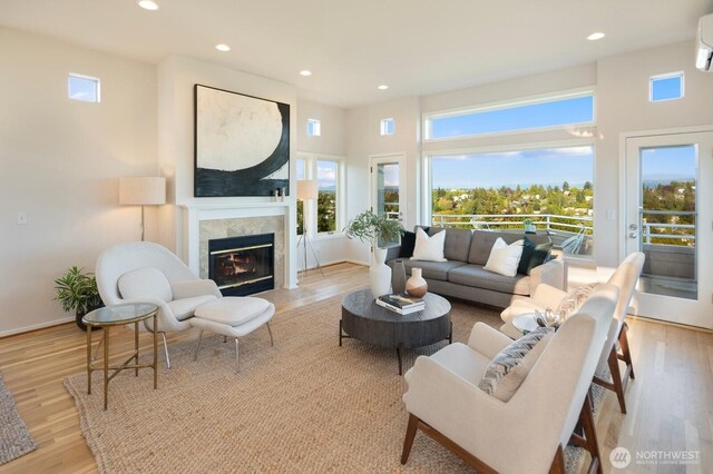 living room featuring a high end fireplace, recessed lighting, light wood-type flooring, a wall mounted AC, and baseboards