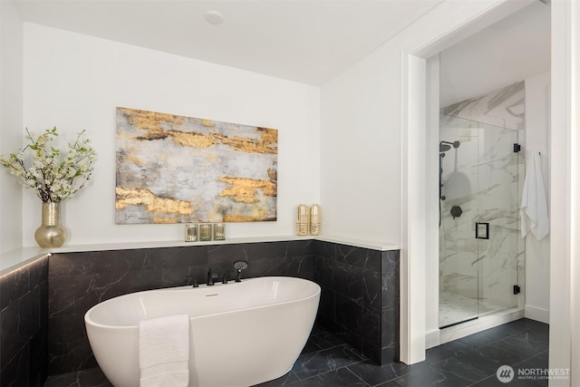 bathroom featuring marble finish floor, a marble finish shower, and a freestanding bath