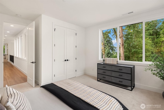 bedroom with a closet, carpet, visible vents, and baseboards