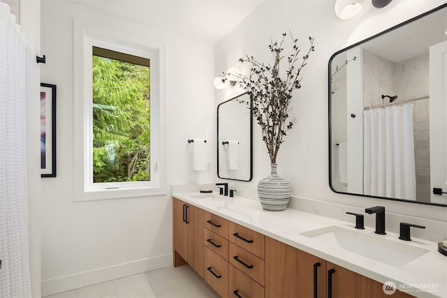bathroom featuring curtained shower, double vanity, baseboards, and a sink
