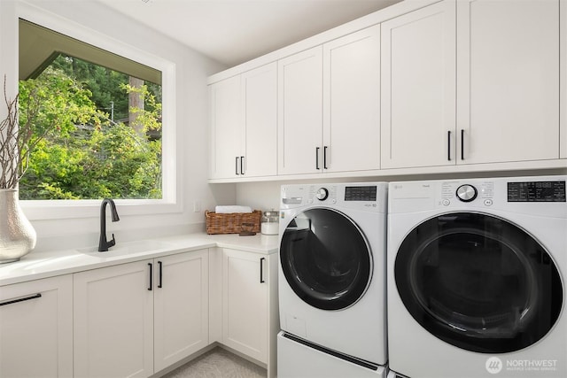 laundry room with cabinet space, a sink, and washer and clothes dryer