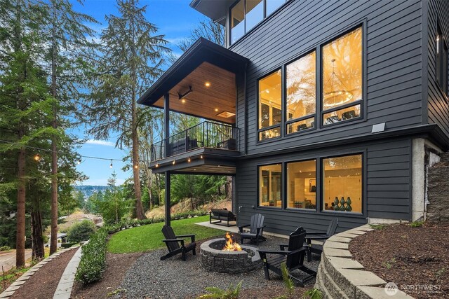 rear view of property with a yard, a patio area, an outdoor fire pit, and a balcony