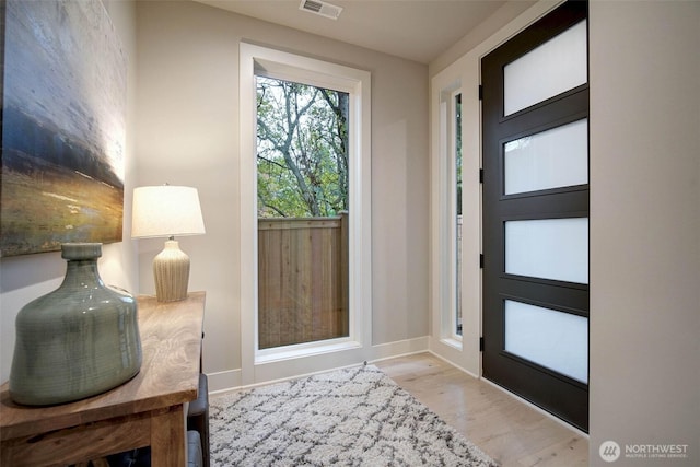 entryway with wood finished floors, visible vents, and baseboards