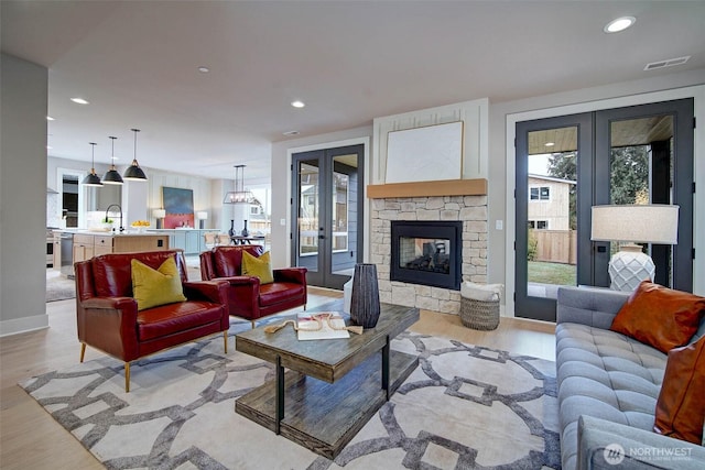 living room with recessed lighting, light wood-style flooring, visible vents, and french doors