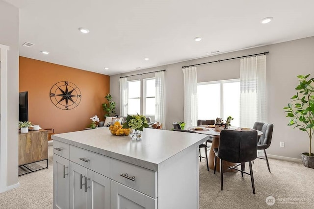 kitchen featuring visible vents, recessed lighting, light carpet, a center island, and light countertops