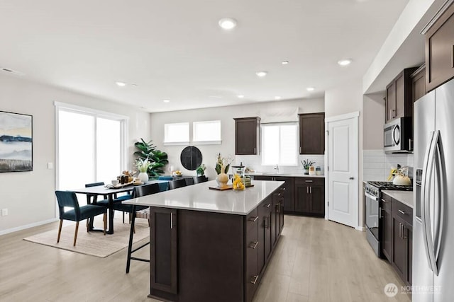 kitchen featuring light countertops, light wood-style floors, dark brown cabinetry, and stainless steel appliances