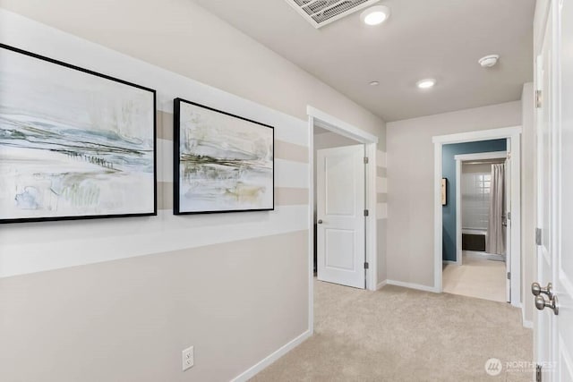 hall with light colored carpet, baseboards, and visible vents