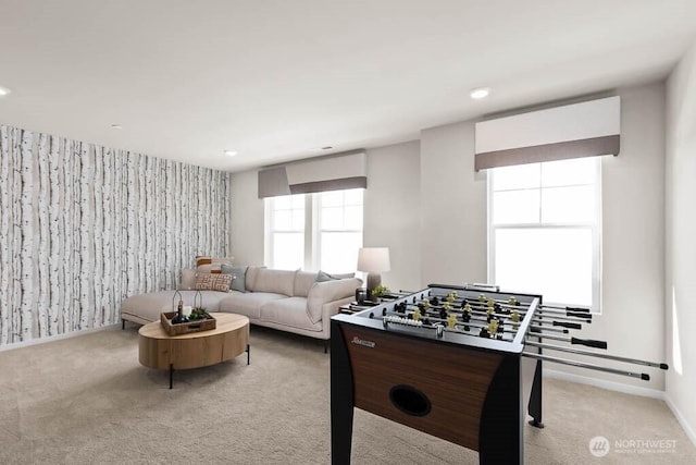 game room featuring wallpapered walls, an accent wall, baseboards, and light carpet