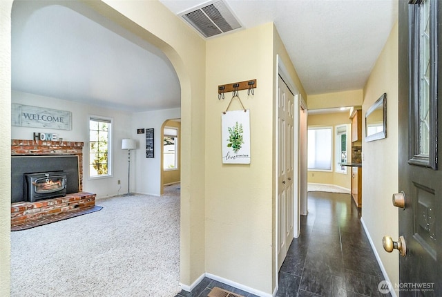 corridor featuring arched walkways, visible vents, and baseboards