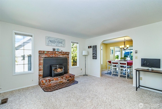 living area featuring a wood stove, visible vents, baseboards, an inviting chandelier, and arched walkways