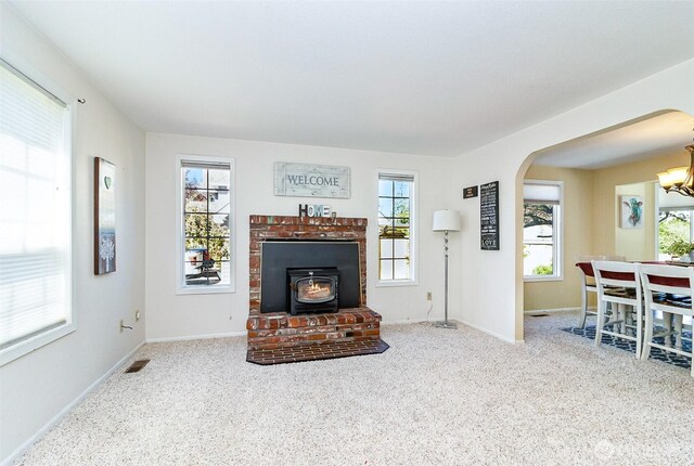 carpeted living area with baseboards, visible vents, arched walkways, and a chandelier
