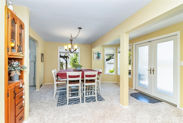 dining space with baseboards, an inviting chandelier, french doors, and light colored carpet