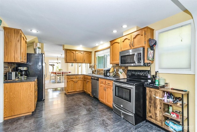 kitchen with a sink, decorative backsplash, brown cabinetry, dark countertops, and appliances with stainless steel finishes