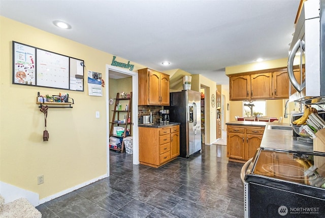 kitchen featuring brown cabinets, appliances with stainless steel finishes, decorative backsplash, and baseboards