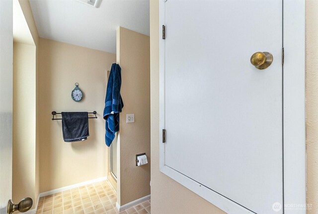 bathroom with an enclosed shower and baseboards