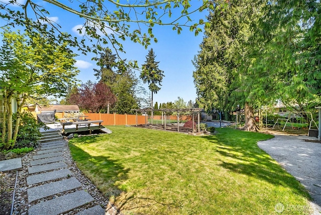 view of yard with fence, a wooden deck, and a vegetable garden