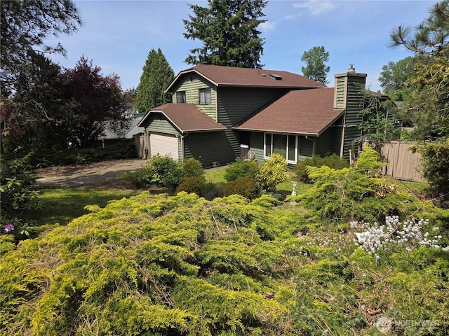 view of front of home with a chimney, driveway, fence, a garage, and roof with shingles