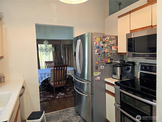 kitchen with appliances with stainless steel finishes, a chandelier, light countertops, and dark wood-type flooring