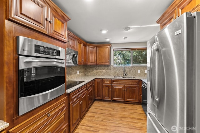6044 Buckthorn Ct NW, Olympia, WA 98502 - kitchen featuring appliances with stainless steel finishes, light stone countertops, a sink, and light wood-style flooring