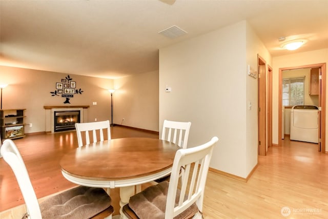 5475 Park Place Loop SE, Lacey, WA 98503 - dining space with washer / clothes dryer, light wood-type flooring, a glass covered fireplace, and baseboards