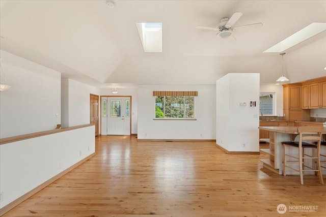 30729 76th Ave NW, Stanwood, WA 98292 - unfurnished living room with a ceiling fan, a skylight, baseboards, light wood-style flooring, and high vaulted ceiling