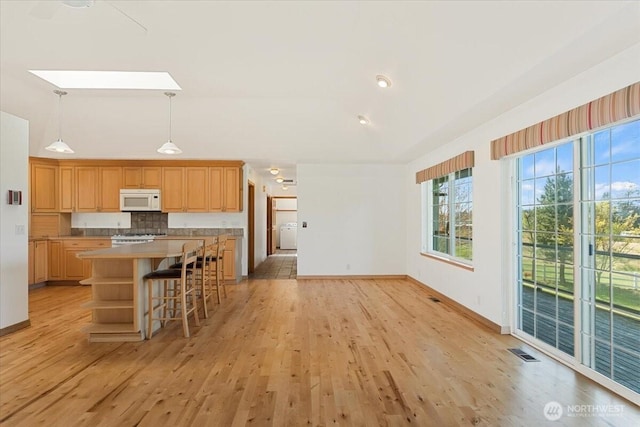 30729 76th Ave NW, Stanwood, WA 98292 - kitchen with visible vents, decorative light fixtures, light wood-type flooring, a center island, and white microwave