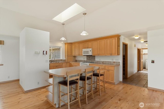 30729 76th Ave NW, Stanwood, WA 98292 - kitchen featuring light wood-style flooring, baseboards, white appliances, light countertops, and a kitchen island
