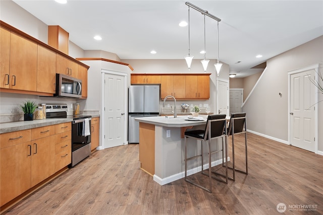 2202 NE 140th St Lot 44, Vancouver, WA 98686 - kitchen with a kitchen island with sink, light wood-style floors, a breakfast bar, light countertops, and appliances with stainless steel finishes