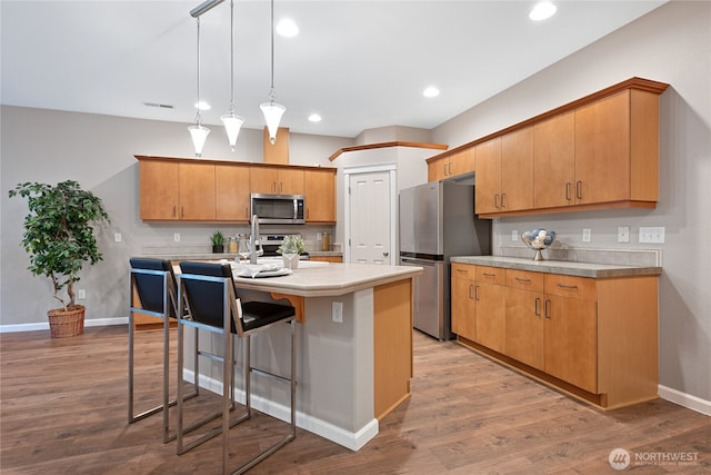 2202 NE 140th St Lot 44, Vancouver, WA 98686 - kitchen with stainless steel appliances, a center island with sink, a breakfast bar area, visible vents, and light countertops