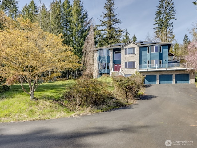view of front of house featuring solar panels, an attached garage, and aphalt driveway