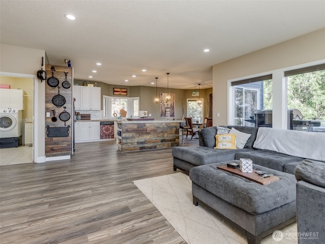 living area with plenty of natural light, washer / dryer, wood finished floors, and recessed lighting