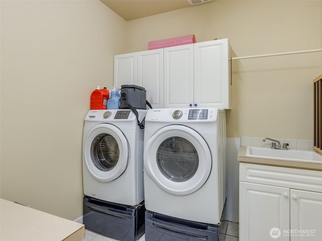 washroom with visible vents, light tile patterned floors, a sink, washer and dryer, and cabinet space