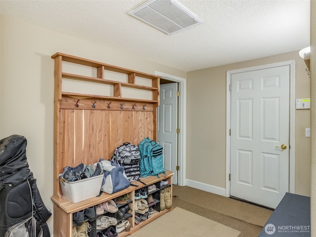 mudroom featuring visible vents, a textured ceiling, and carpet flooring