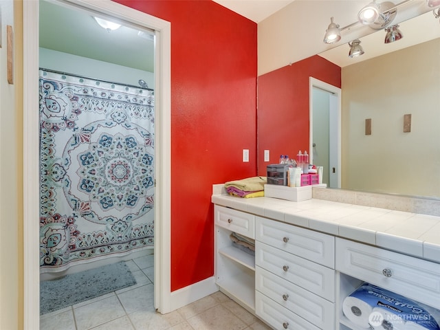 bathroom with curtained shower, vanity, and tile patterned flooring