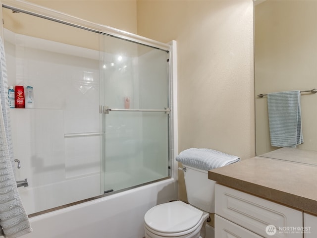 bathroom featuring combined bath / shower with glass door, vanity, and toilet