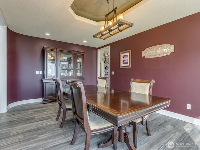 dining area with baseboards, wood finished floors, recessed lighting, and a chandelier