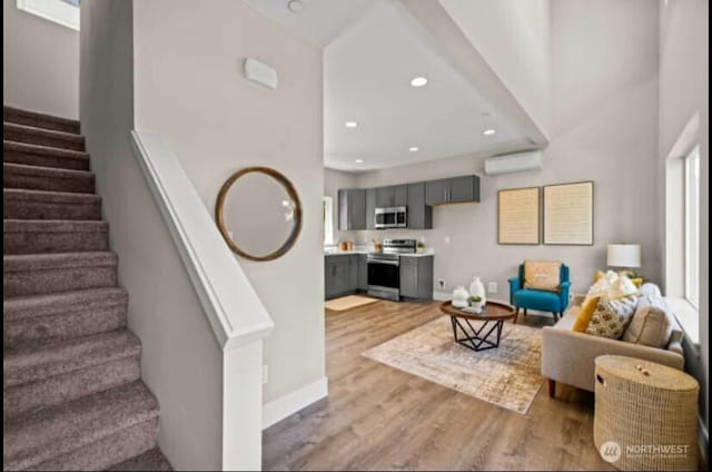living area featuring recessed lighting, baseboards, stairs, and light wood-style flooring
