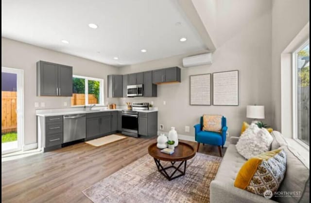 living room featuring recessed lighting, light wood-style flooring, a healthy amount of sunlight, and a wall mounted air conditioner