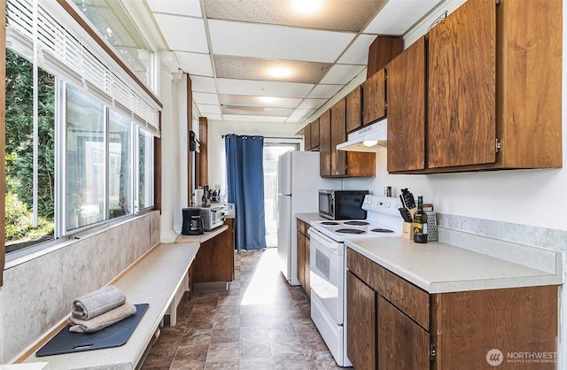 3512 Grand Ave, Everett, WA 98201 - kitchen featuring a wealth of natural light, under cabinet range hood, white appliances, and light countertops