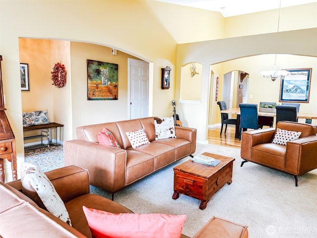 living area featuring arched walkways, baseboards, light carpet, and a chandelier