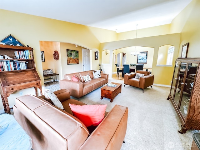 living room with baseboards, arched walkways, a notable chandelier, and carpet flooring