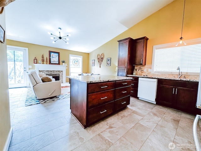 kitchen with a center island, a fireplace, light stone countertops, dishwasher, and lofted ceiling