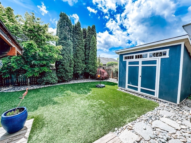 view of yard with a fenced backyard, an outbuilding, and a shed