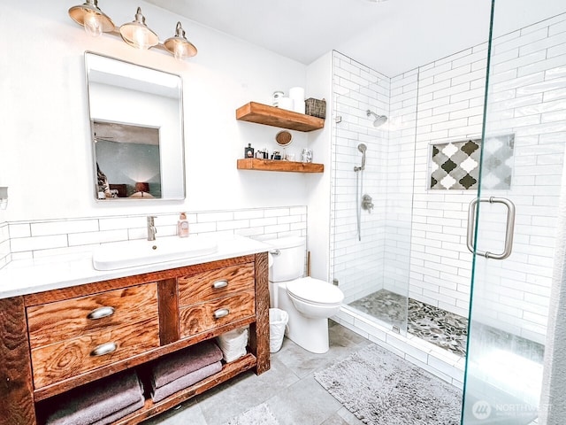 bathroom featuring vanity, tile patterned flooring, toilet, tile walls, and a shower stall