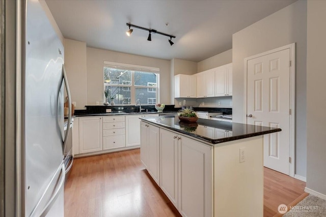 3116 164th St SW Unit 2101, Lynnwood, WA 98087 - kitchen with freestanding refrigerator, light wood finished floors, a sink, rail lighting, and white cabinetry
