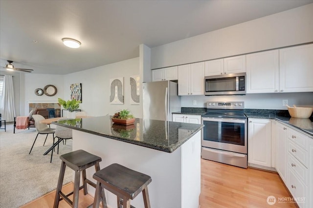 3116 164th St SW Unit 2101, Lynnwood, WA 98087 - kitchen with stainless steel appliances, a breakfast bar, white cabinets, and a ceiling fan