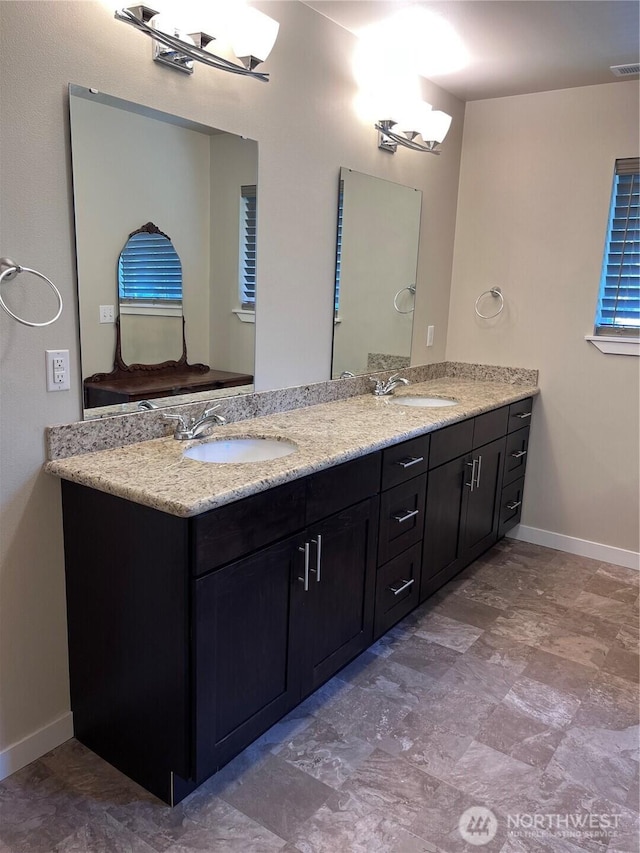 full bath featuring a sink, double vanity, and baseboards