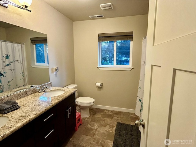 full bathroom featuring double vanity, toilet, a sink, visible vents, and baseboards