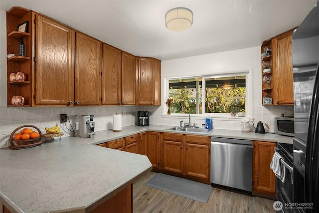 kitchen featuring open shelves, a sink, stainless steel appliances, light countertops, and a peninsula